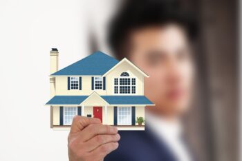 A real estate agent holding an illustration of a house